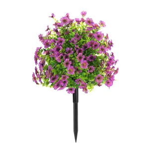 Detailweergave van kunstmatige paarse viooltjes met groene bladeren op een zwarte tuinsteker