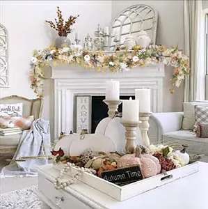 Detail of autumn garland featuring white pumpkins, maple leaves, and striped bows on a mantel