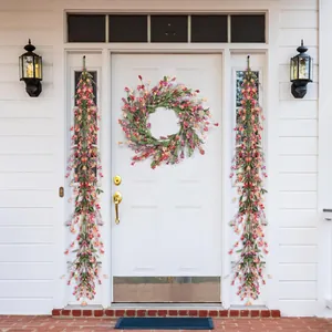 Detail of colorful artificial daisy wreath and floral vines on a white front door