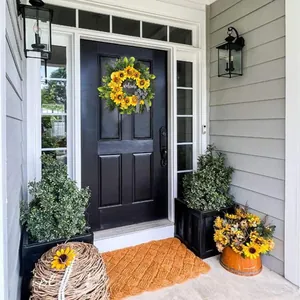 Close-up of decorative sunflower wreath with welcome sign and bow on a black front door