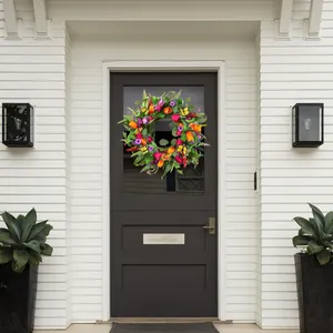 Détail d'une couronne de tulipes colorées avec des papillons sur une porte sombre