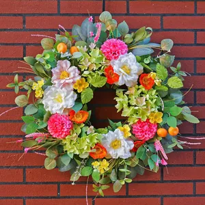 Detail of colorful wildflower wreath with pink dahlias and peonies on red brick wall