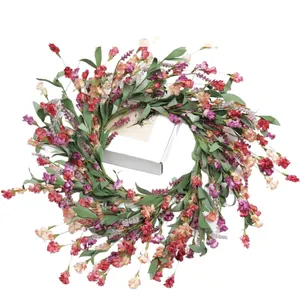 Artificial spring floral wreath with colorful daisies and greenery on white gift box backdrop