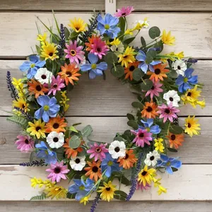 Colorful artificial spring daisy wreath with mixed wildflowers on a rustic wooden background