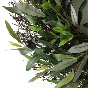 Close-up of lifelike artificial olive wreath with green leaves and black olives on twigs