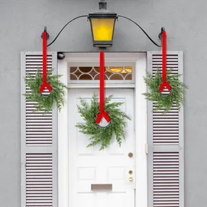 Set of three green Christmas wreaths with red ribbons hanging on white doors and windows