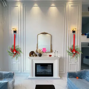 Pair of Christmas pine wreaths with red berries and ribbons hung over a cozy fireplace