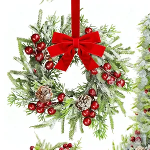 Détail de couronne de Noël avec aiguilles de pin enneigées, baies rouges et pommes de pin