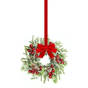 Couronne de Noël avec aiguilles de pin enneigées, baies rouges et nœud en velours