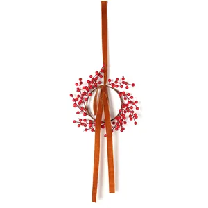 Detail of a Christmas wreath featuring vibrant red berries and a brown velvet hanging ribbon