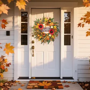 Close-up of autumn harvest wreath with pumpkins and sunflowers hanging on a white front door