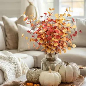 Detail of autumn eucalyptus stems with gradient red and orange leaves in a glass vase