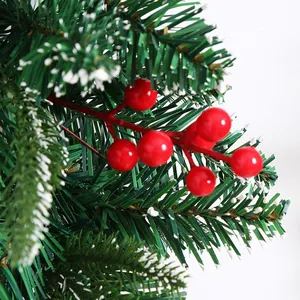 Detailed view of snowy Christmas pine needle branches with vibrant red festive berries