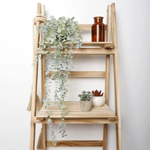 Artificial hanging eucalyptus plant in black pot on wooden ladder for home wall decor