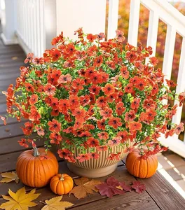 Artificial orange petunias and eucalyptus in a ribbed beige pot with autumn decor