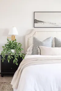 Artificial striped hanging plant in white pot placed on a modern bedroom nightstand