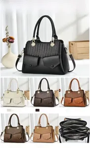 Detail view of woven leather panel and metallic magnetic snaps on women's handbag