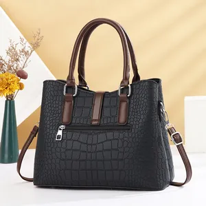 Elegant black crocodile pattern handbag with brown handles and adjustable shoulder strap