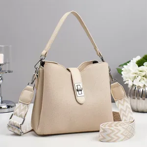 Detalle de bolso beige de tela texturizada con cierre de giro plateado y correa de diseño