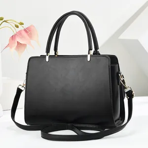 Detalle del bolso cuadrado de cuero negro con herrajes dorados y correa desmontable