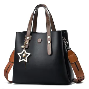 Women's black pebbled leather bucket bag with brown straps and star charm accessory