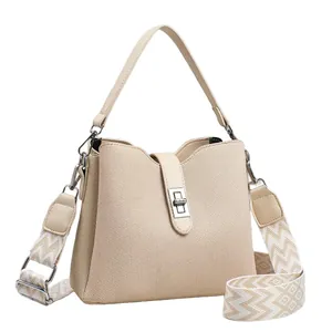 Elegante bolso de lona beige con correa geométrica y cierre de bloqueo giratorio de metal