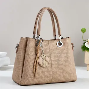 Detail of embossed geometric pattern and round metal pendant on beige tote bag
