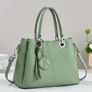 Close-up of light green handbag featuring geometric embossed pattern and silver hardware