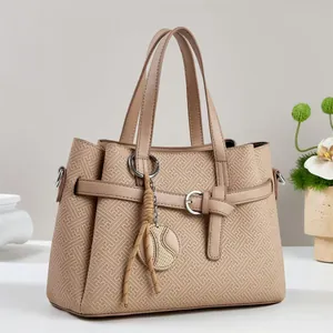 Macro detail of beige tote bag showing geometric textured embossing and fringe tassel