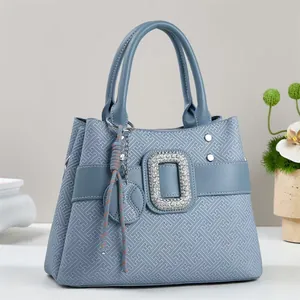 Detail of light blue faux leather handbag with geometric pattern and rhinestone buckle