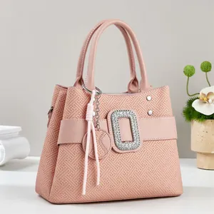 Close-up of geometric textured pink handbag with rhinestone buckle and tassel detail