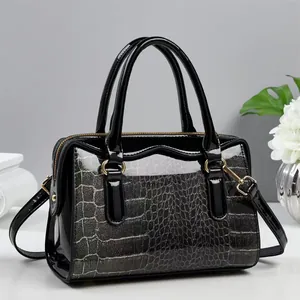 Detail of glossy black patent leather with grey crocodile texture on a shoulder bag