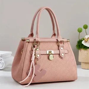 Detail of pink tote bag showing geometric embossing, gold hardware, and heart tassel