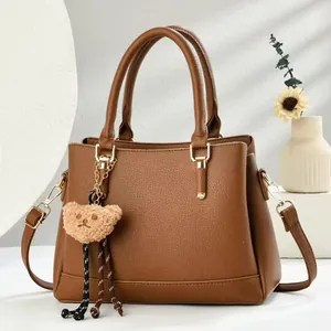 Brown litchi grain leather Boston bag with plush bear charm and gold hardware