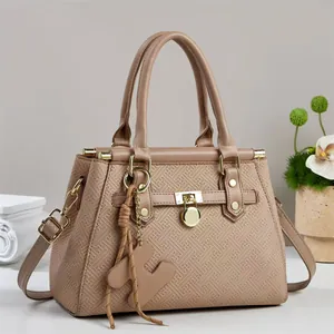 Detail view of earth-tone tote bag with geometric embossing and gold hardware lock
