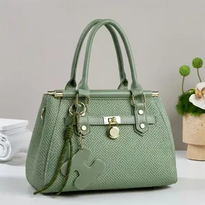Detail of light green tote bag with geometric embossed texture and golden twist lock