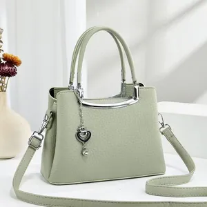 Détail d'un sac à main en cuir vert menthe avec garniture argentée et pendentif cœur