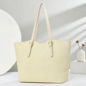 Detail van beige tote bag met V-vormige textuur en metalen verstelbare gesp detail