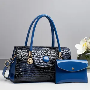 Detail von blauem Handtaschen-Set mit Krokodilprägung, goldenem Löwenanhänger und Geldbörse