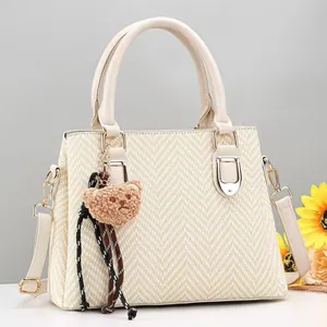 Detailed view of beige textured shoulder bag with plush bear charm and sunflower accent