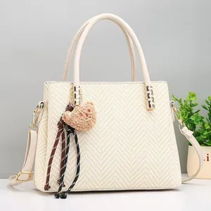 Detail of off-white woven handbag with cute bear charm and gold-tone hardware