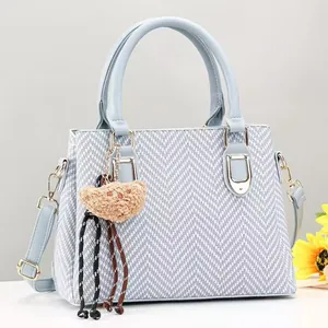 Detail of blue-grey knit handbag featuring leather handles and gold metal hardware