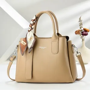 Détail du sac à main beige en cuir grainé avec foulard en soie et bandoulière réglable