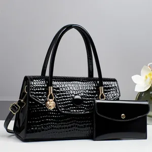 Detail der schwarzen Handtasche mit Krokoprägung, Löwenanhänger und passender Geldbörse