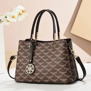 Detailed macro view of vintage brown monogram handbag with gold floral pendant and leather strap