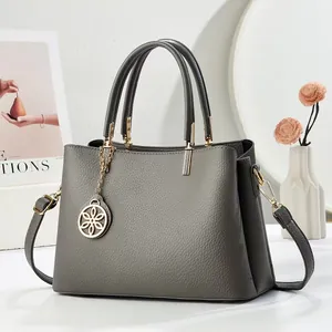 Sac à main en cuir grainé gris avec pendentif fleur dorée et bandoulière réglable