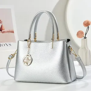 Sac à main argenté en cuir grainé avec détails dorés et pendentif floral élégant
