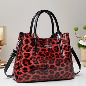 Detalle del bolso tote con estampado de leopardo rojo, acabado brillante y metal plateado