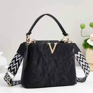 Borsa a mano nera minimalista con fibbia a V dorata e tracolla geometrica larga