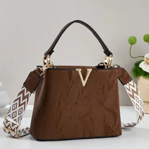 Borsa a mano marrone in pelle cerata con logo V dorato e tracolla larga decorata